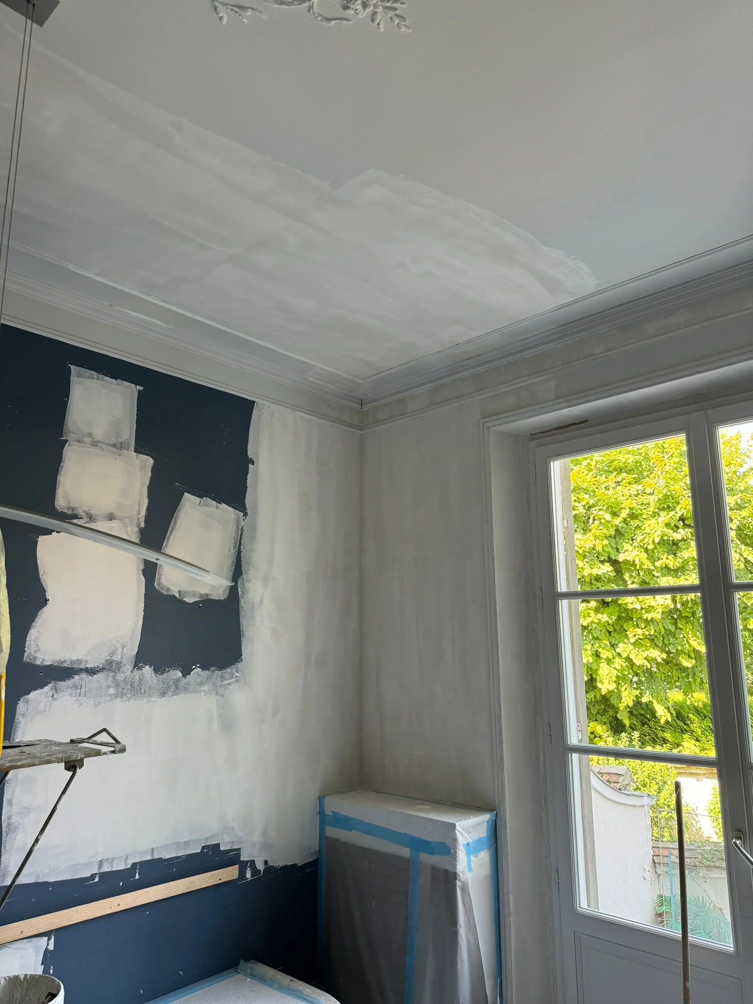 Pièce en cours de peinture, mur bleu marine avec essais de couleur