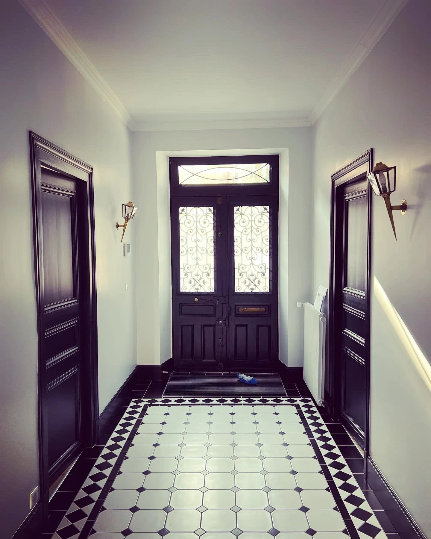 Même couloir repeint en blanc, portes noires et sol en damier